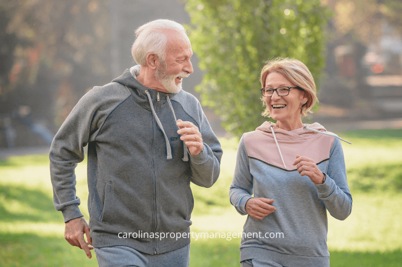 A smiling senior couple jogging together in a sunny park, enjoying an active lifestyle. This image represents the quality of life and peace of mind provided by Carolina Property Management, the #1 property management company in Charlotte, NC, offering well-maintained rental homes for comfortable living.