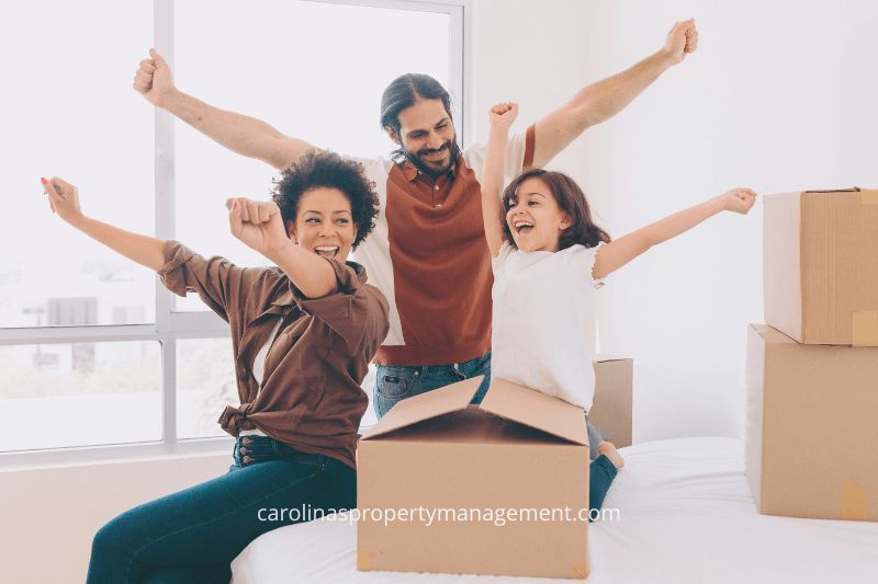 A joyful family celebrating in their new home, surrounded by moving boxes. This image symbolizes the seamless and stress-free moving experience provided by Carolina Property Management to help families find their perfect home.